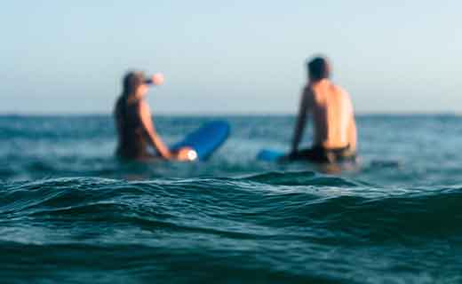 surf lessons 3 two people in the water taking surf lessons